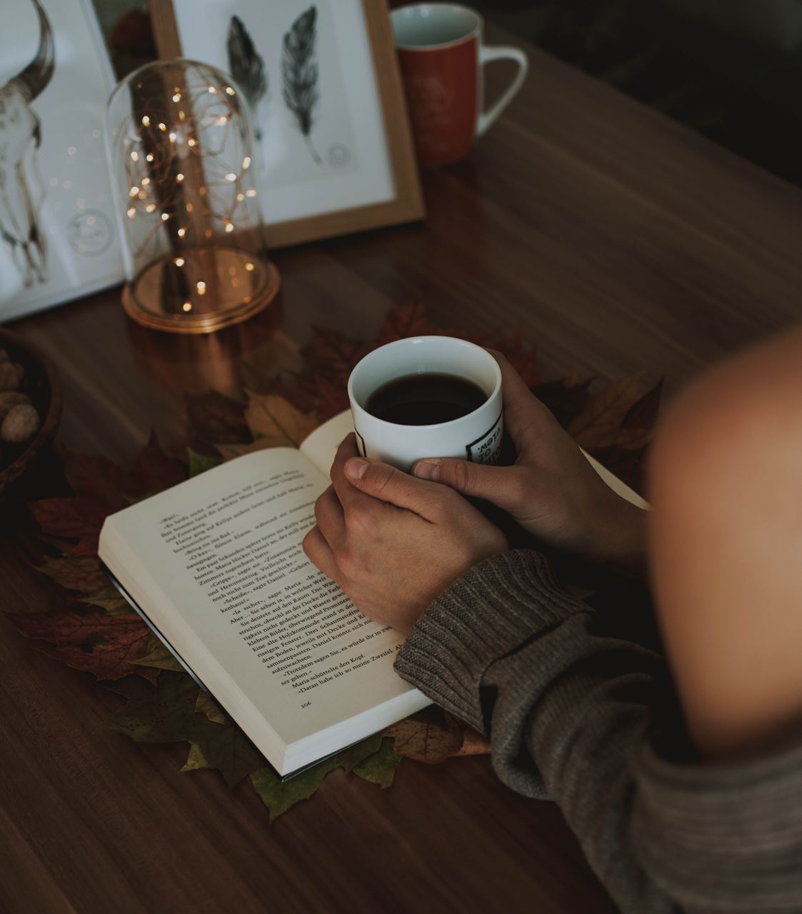 Hands holding cup of coffee on open book